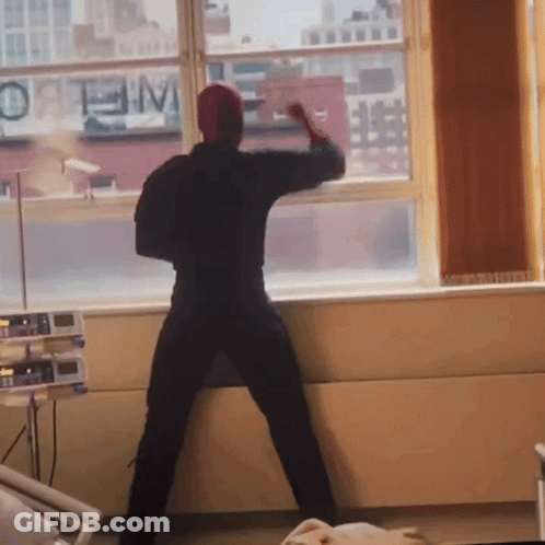 A Man Stands In Front Of A Window With A Sign That Says Optimum GIF