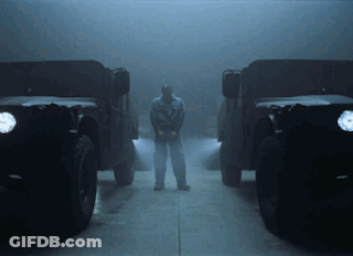 A Man Stands In Front Of Two Military Vehicles GIF
