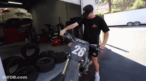 A Man Stands Next To A Motorcycle With The Number 28 On The Front GIF