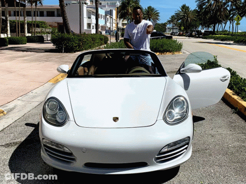 A Man Stands Next To A White Porsche Convertible GIF