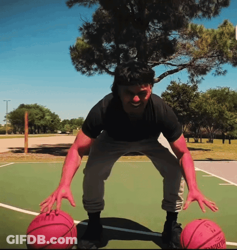A Man Stands On A Basketball Court Holding Two Pink Basketballs One Of Which Has The Number 13 On The Back GIF