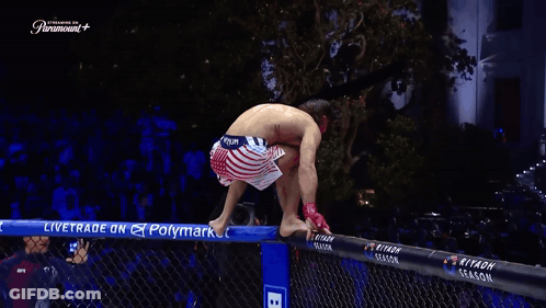 A Man Stands On A Fence With His Arms Outstretched In Front Of A Paramount Sign GIF