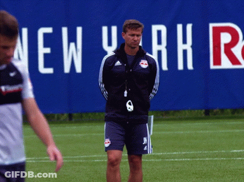 A Man Stands On A Field In Front Of A New York Sign GIF