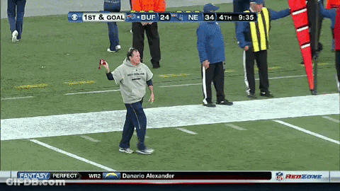 A Man Stands On A Football Field Holding A Ball In Front Of A Scoreboard That Says 1St And Goal GIF