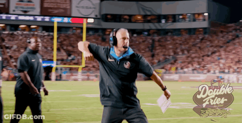 A Man Stands On A Football Field With A Double Fries Logo In The Background GIF
