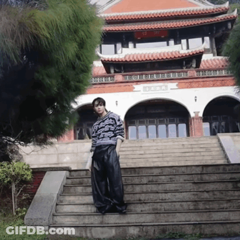 A Man Stands On A Set Of Stairs In Front Of A Building With Chinese Writing GIF