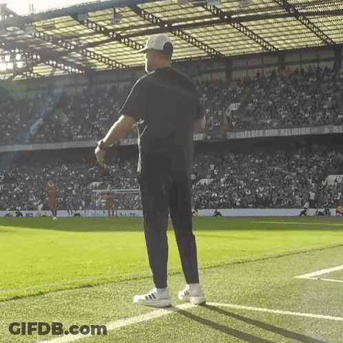 A Man Stands On A Soccer Field In Front Of A Sign That Says Chelsea And Religion GIF
