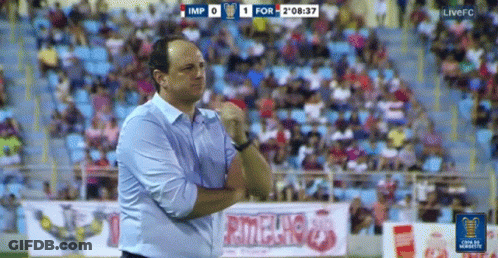 A Man Stands On A Soccer Field In Front Of A Sign That Says ' Rionegro ' GIF