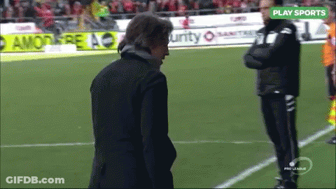 A Man Stands On A Soccer Field With A Play Sports Sign Above Him GIF