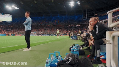 A Man Stands On A Soccer Field With A Sign That Says Stadium On It GIF