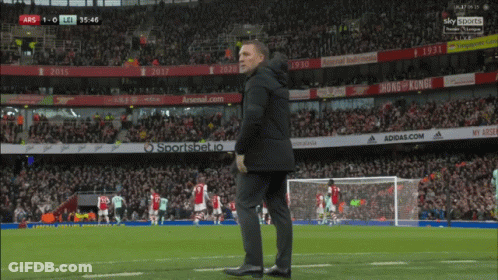 A Man Stands On A Soccer Field With Ads For Adidas.com And Arsenal.com In The Background GIF