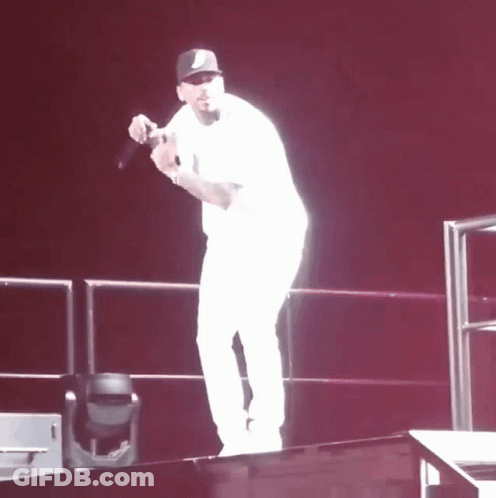 A Man Stands On A Stage Holding A Microphone In His Hand GIF