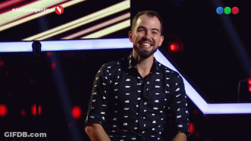 A Man Stands On A Stage In Front Of A Microphone With The Hashtag La Voz Argentina GIF