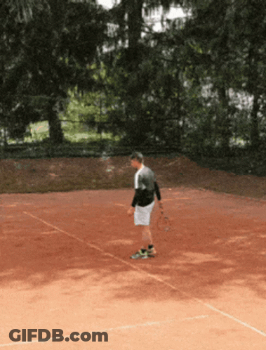 A Man Stands On A Tennis Court Holding A Racket GIF