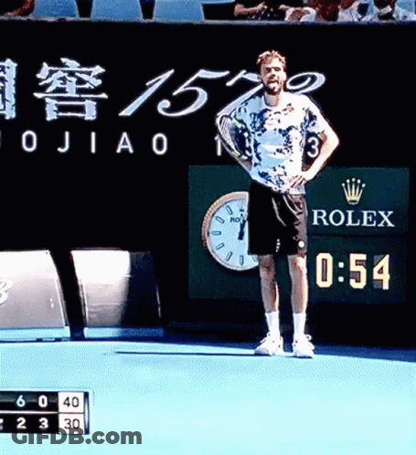 A Man Stands On A Tennis Court With A Rolex Sign Behind Him GIF