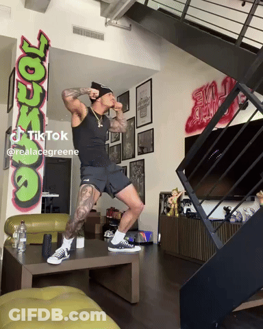 Man Standing On One Leg In Front Of Graffiti GIF
