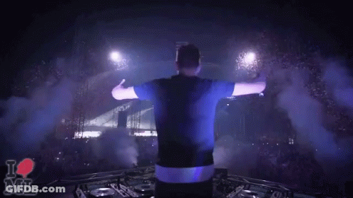 A Man Stands On Stage With His Arms Outstretched In Front Of A Crowd And A Sign That Says " I Love Mil " GIF