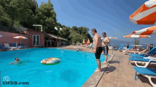 A Man Stands On The Edge Of A Swimming Pool Looking At A Float In The Water GIF