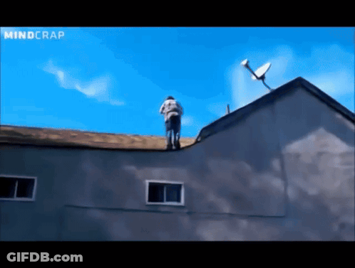 A Man Stands On The Roof Of A Building With A Satellite Dish On Top Of It GIF