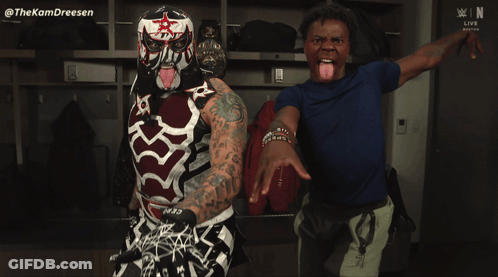 A Man Sticking His Tongue Out Next To A Wrestler With A Mask On GIF
