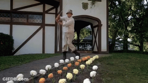 A Man Swinging A Golf Club In Front Of A Building With A Shield On It GIF