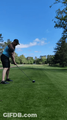 A Man Swings A Golf Club At A Golf Ball GIF