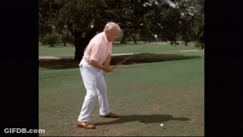 A Man Swings A Golf Club At A Golf Ball GIF