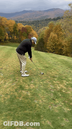 A Man Swings A Golf Club On A Golf Course GIF