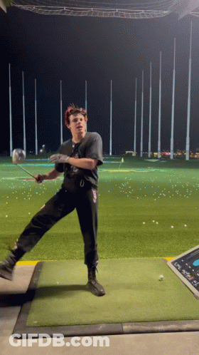 A Man Swings A Golf Club On A Golf Course GIF