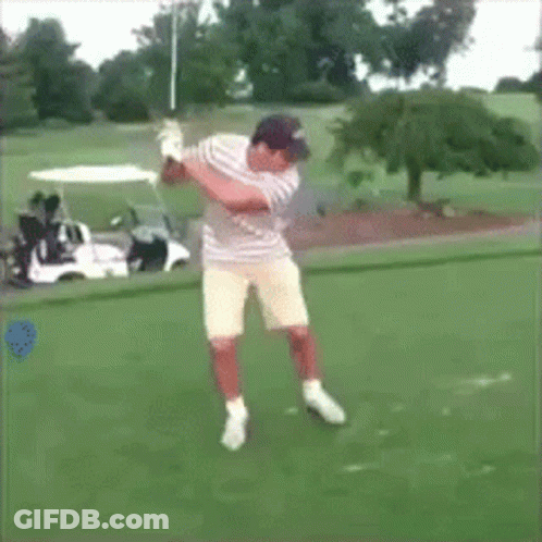 A Man Swings A Golf Club On A Golf Course In Front Of A Golf Cart GIF