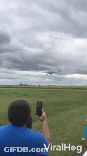 A Man Takes A Picture Of An Airplane Taking Off From A Runway With Viralhog Written On The Bottom GIF