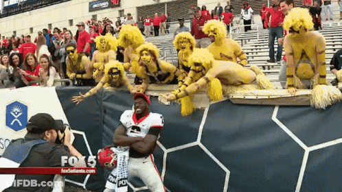 A Man Taking A Picture Of A Football Player In Front Of A Fox 5 Banner GIF