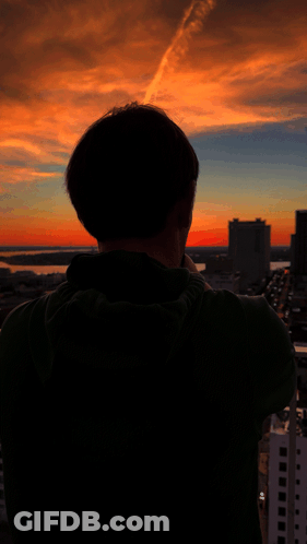 A Man Taking A Picture Of A Sunset With His Cell Phone GIF