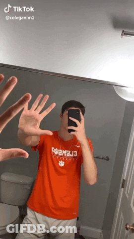A Man Taking A Picture Of Himself In A Mirror With His Hands In The Air GIF