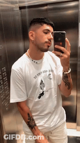 A Man Taking A Picture Of Himself In An Elevator Wearing A Shirt That Says ' 310 ' On It GIF