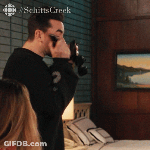 A Man Taking A Picture With A Camera With #Schitts Creek On The Bottom GIF