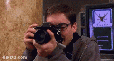 A Man Taking A Picture With A Camera With The Word Oceana On The Screen Behind Him GIF