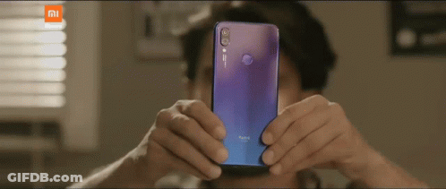 A Man Taking A Picture With A Purple Redmi Phone GIF
