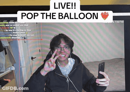 A Man Taking A Selfie In Front Of A Screen That Says " Live Pop The Balloon " GIF