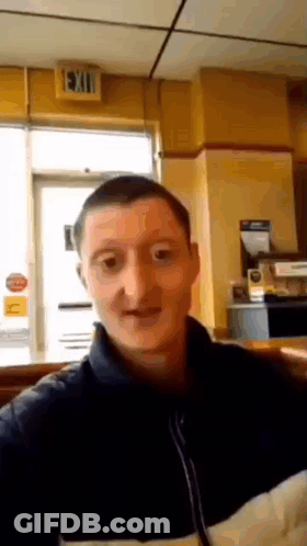 A Man Taking A Selfie In Front Of A Sign That Says Exit GIF