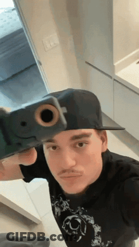 A Man Taking A Selfie With A Gun In His Hand GIF