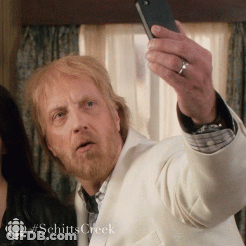 A Man Taking A Selfie With #Schittscreek Written On The Bottom GIF