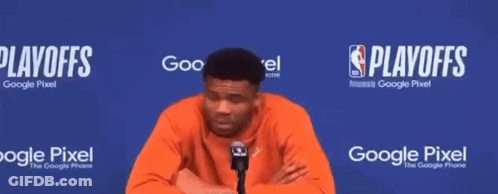 A Man Talking Into A Microphone In Front Of A Blue Wall That Says Playoffs On It GIF