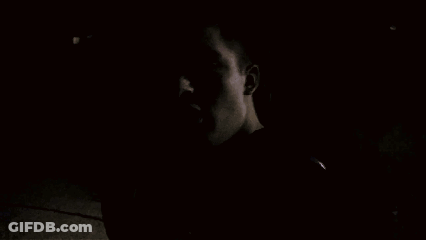 A Man Talking On A Cell Phone In A Dark Room GIF