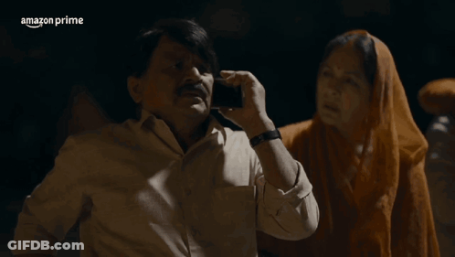 A Man Talking On A Cell Phone Next To A Woman With Ayee Sasur Written In White GIF