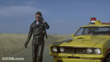 A Man Talking On A Cell Phone Next To A Yellow Car With A Red Light On Top GIF