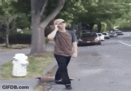 A Man Talking On A Cell Phone While Walking Down A Street GIF