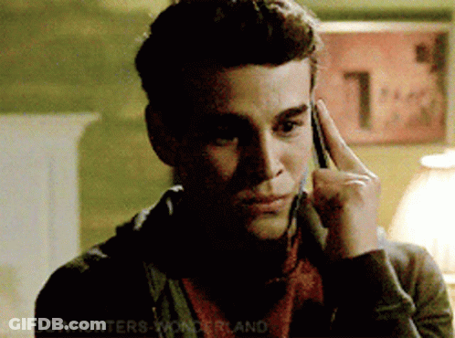 A Man Talking On A Cell Phone With A Sign In The Background That Says 1 GIF