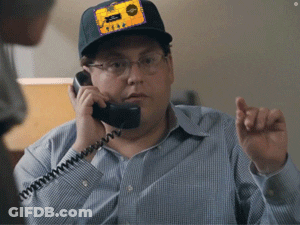 A Man Talking On A Phone With A Patch On His Hat That Says ' Texas ' On It GIF