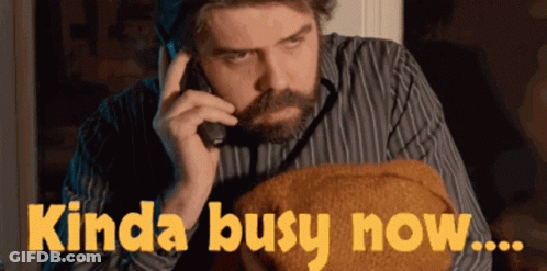 A Man Talking On A Phone With The Words Kinda Busy Now Written Below Him GIF
